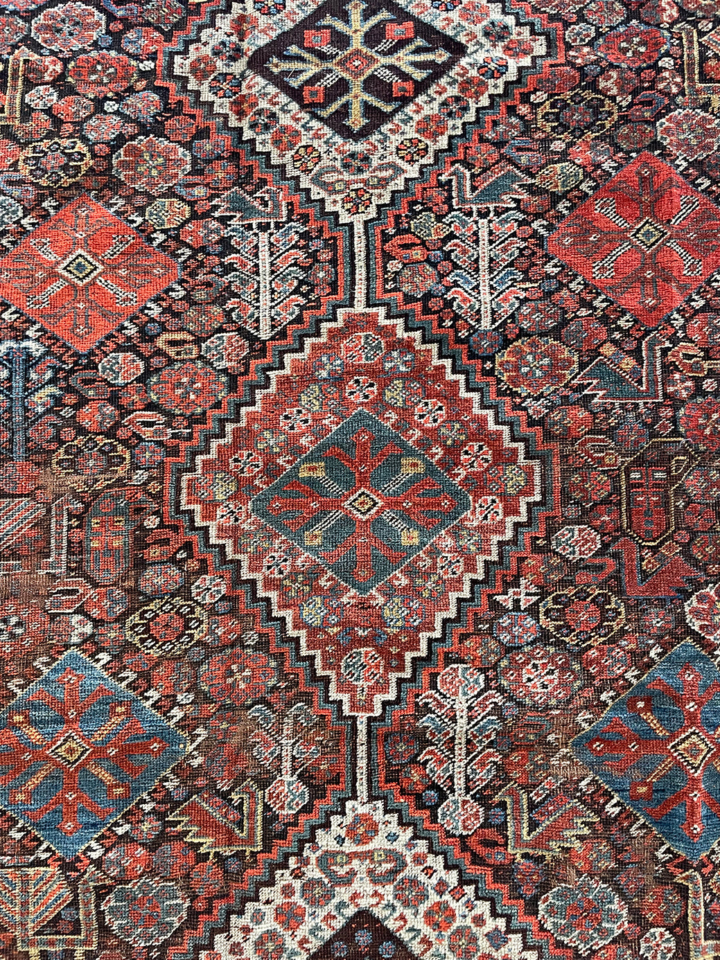 an antique qashqai rug with a dark blue field and intricate colourful details