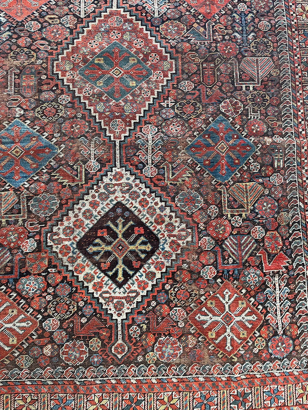 an antique qashqai rug with a dark blue field and intricate colourful details