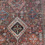 an antique qashqai rug with a dark blue field and intricate colourful details
