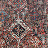an antique qashqai rug with a dark blue field and intricate colourful details