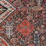 an antique qashqai rug with a dark blue field and intricate colourful details