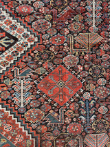 an antique qashqai rug with a dark blue field and intricate colourful details
