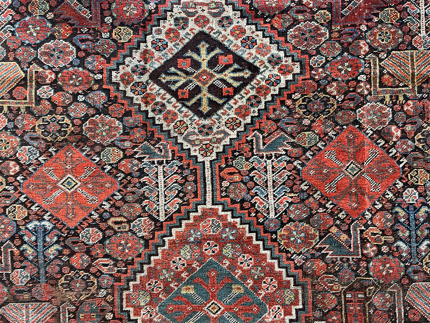 an antique qashqai rug with a dark blue field and intricate colourful details