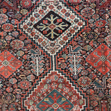 an antique qashqai rug with a dark blue field and intricate colourful details
