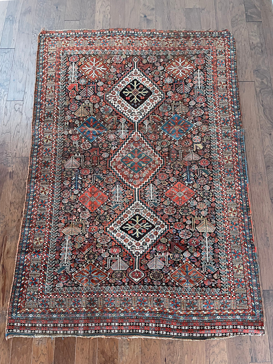 an antique qashqai rug with a dark blue field and intricate colourful details