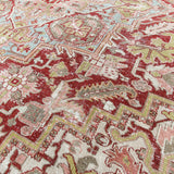 Close-up of a patterned rug with red, beige, and green colors.