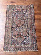 an antique shiraz qashqai rug with a dark blue field and brick red medallions