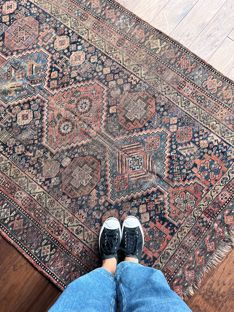 an antique shiraz qashqai rug with a dark blue field and brick red medallions