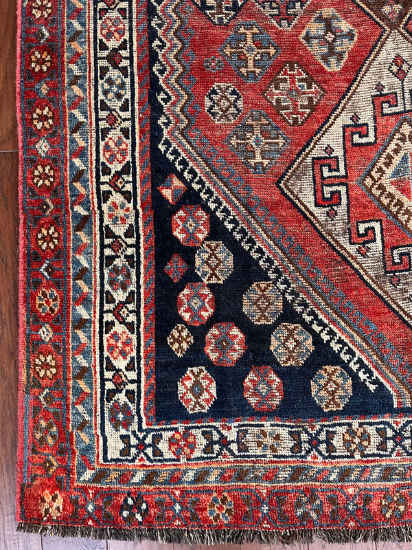 an antique qashqai rug with a red and blue palette and large central medallion