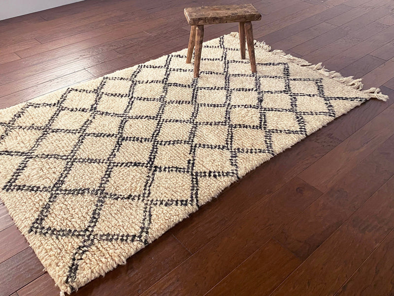 a vintage berber rug circa 1970 with a black trellis pattern on a neutral wool field