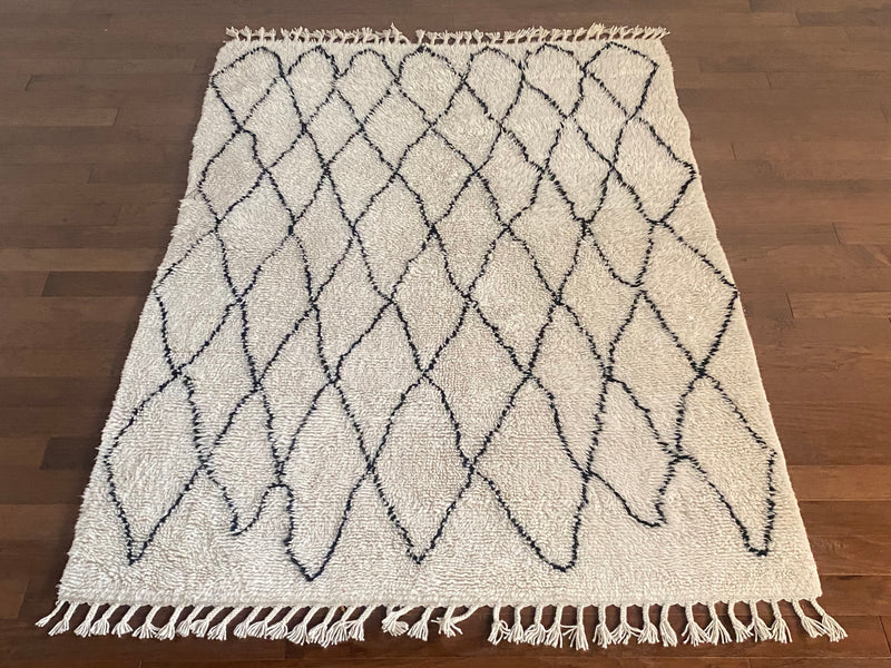 a vintage berber rug with uneven black diamond pattern on a cream field