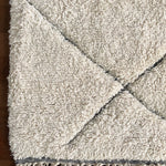 a large vintage berber rug with undyed wool and a large black diamond pattern