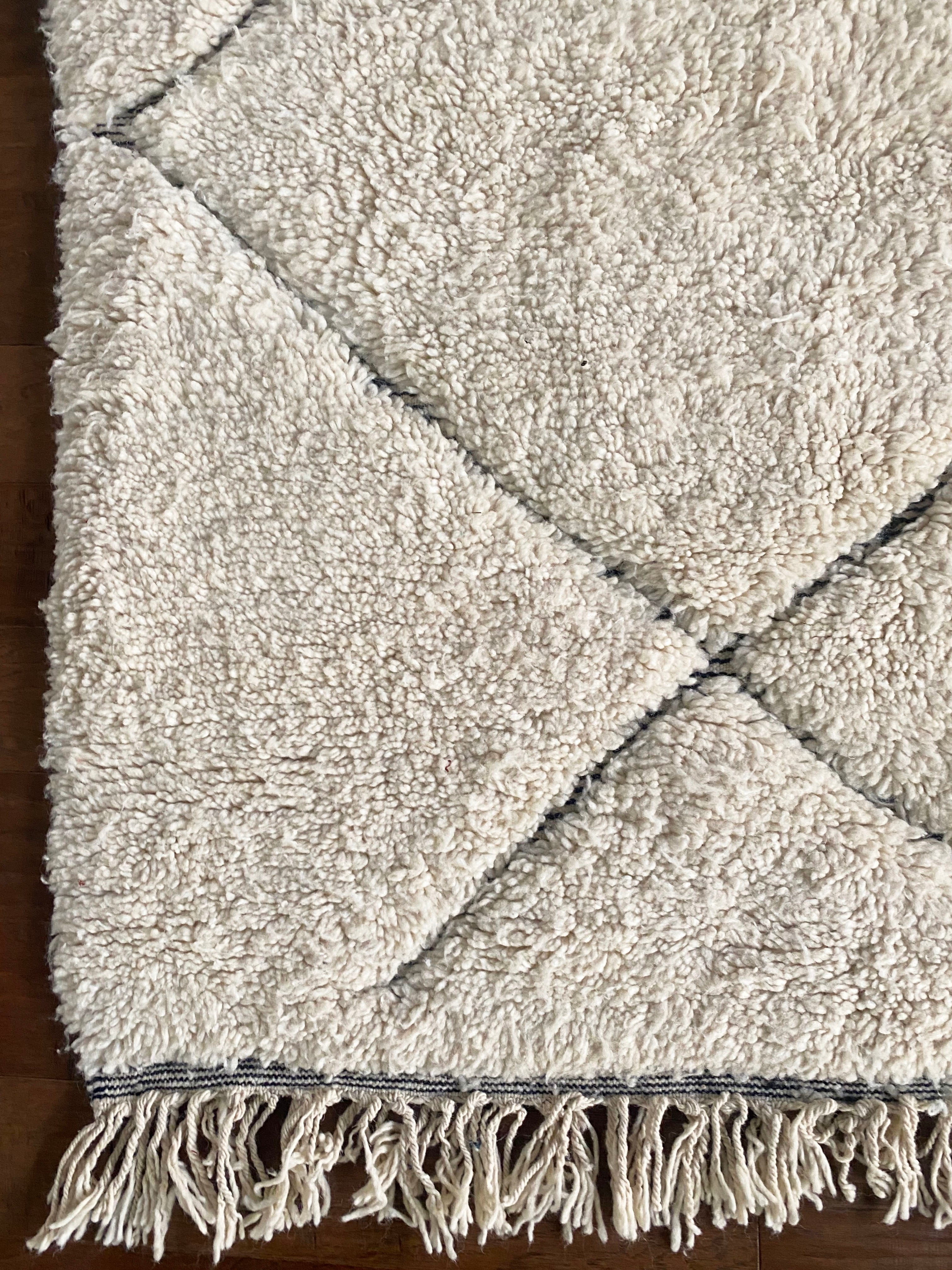 a large vintage berber rug with undyed wool and a large black diamond pattern