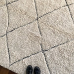 a large vintage berber rug with undyed wool and a large black diamond pattern