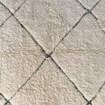 a large vintage berber rug with undyed wool and a large black diamond pattern