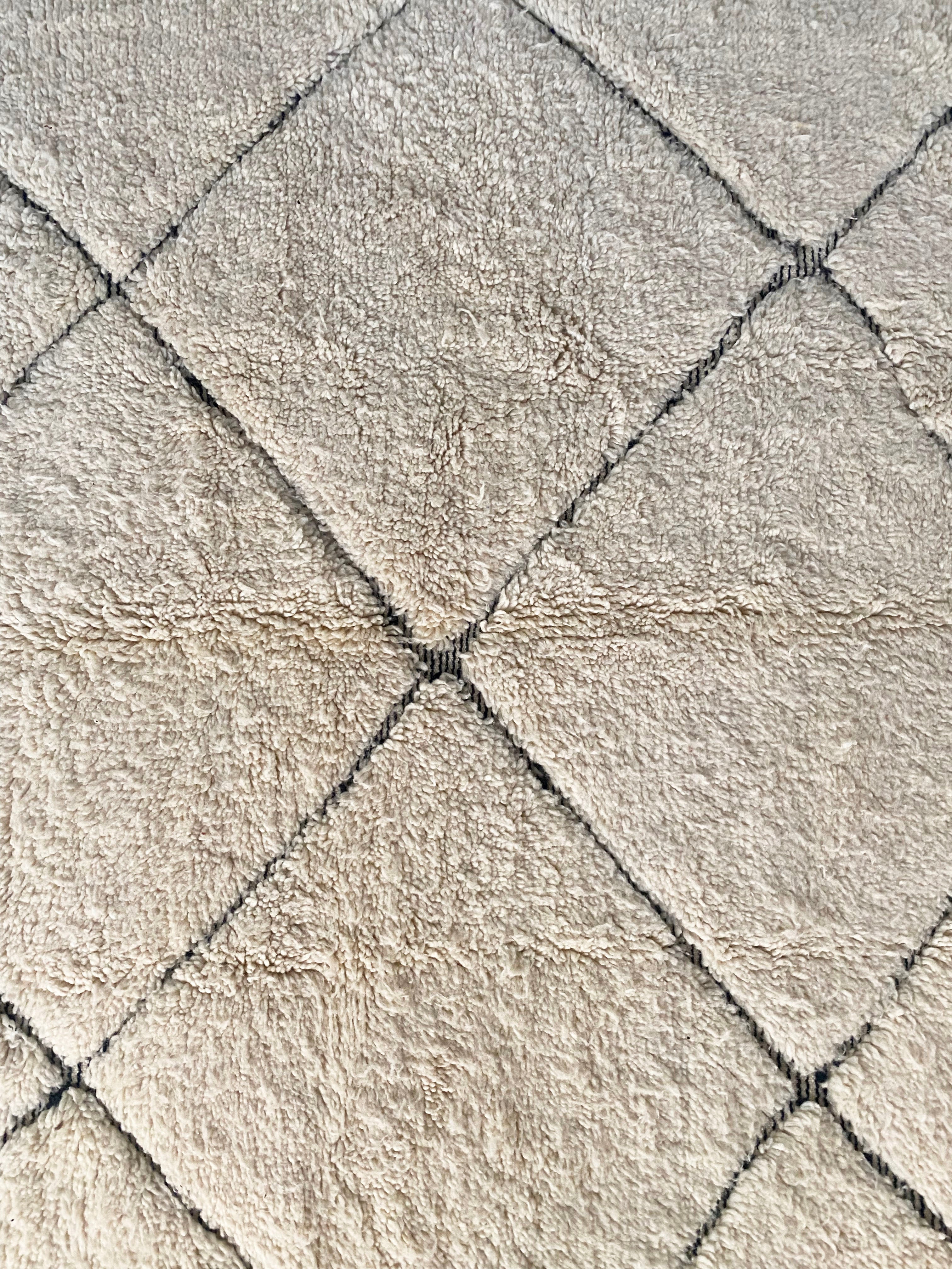 a large vintage berber rug with undyed wool and a large black diamond pattern