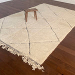 a large vintage berber rug with undyed wool and a large black diamond pattern