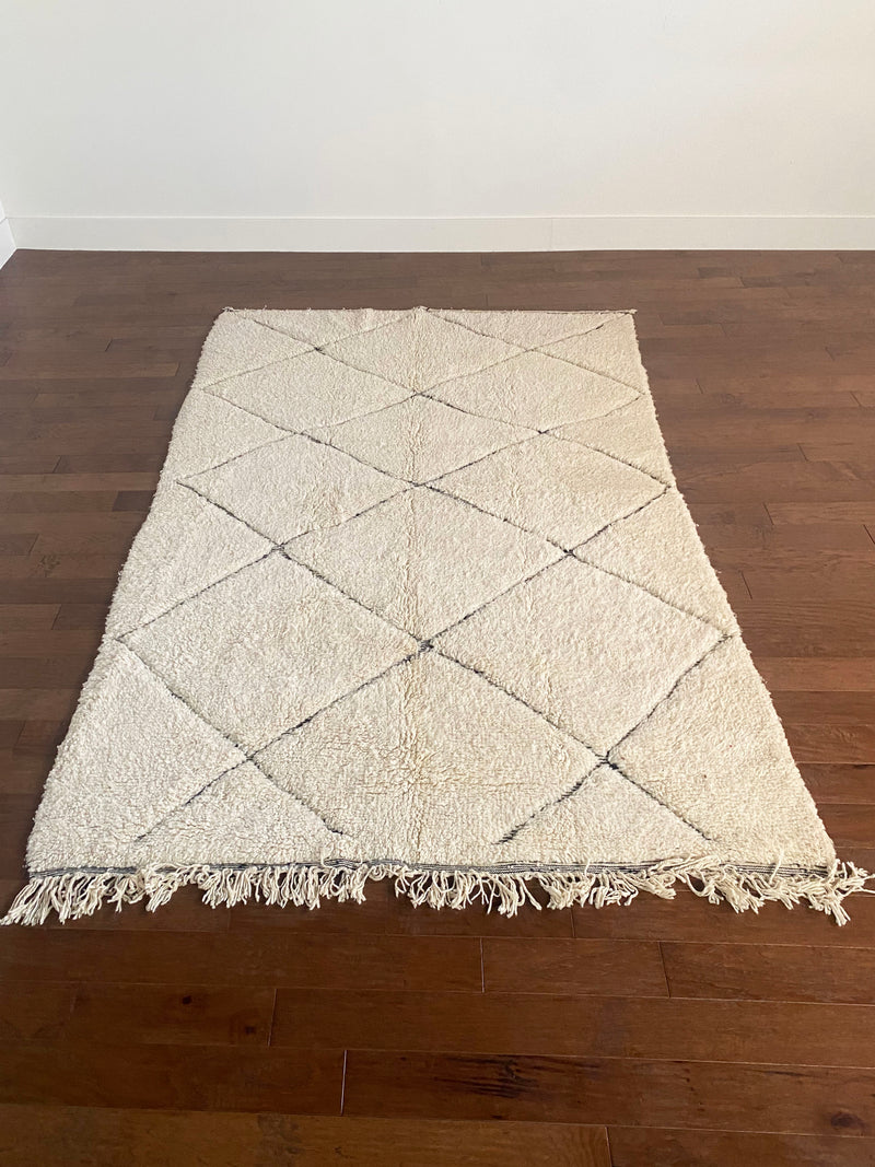 a large vintage berber rug with undyed wool and a large black diamond pattern