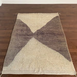 a vintage berber rug with two large taupe diamonds on a cream wool field