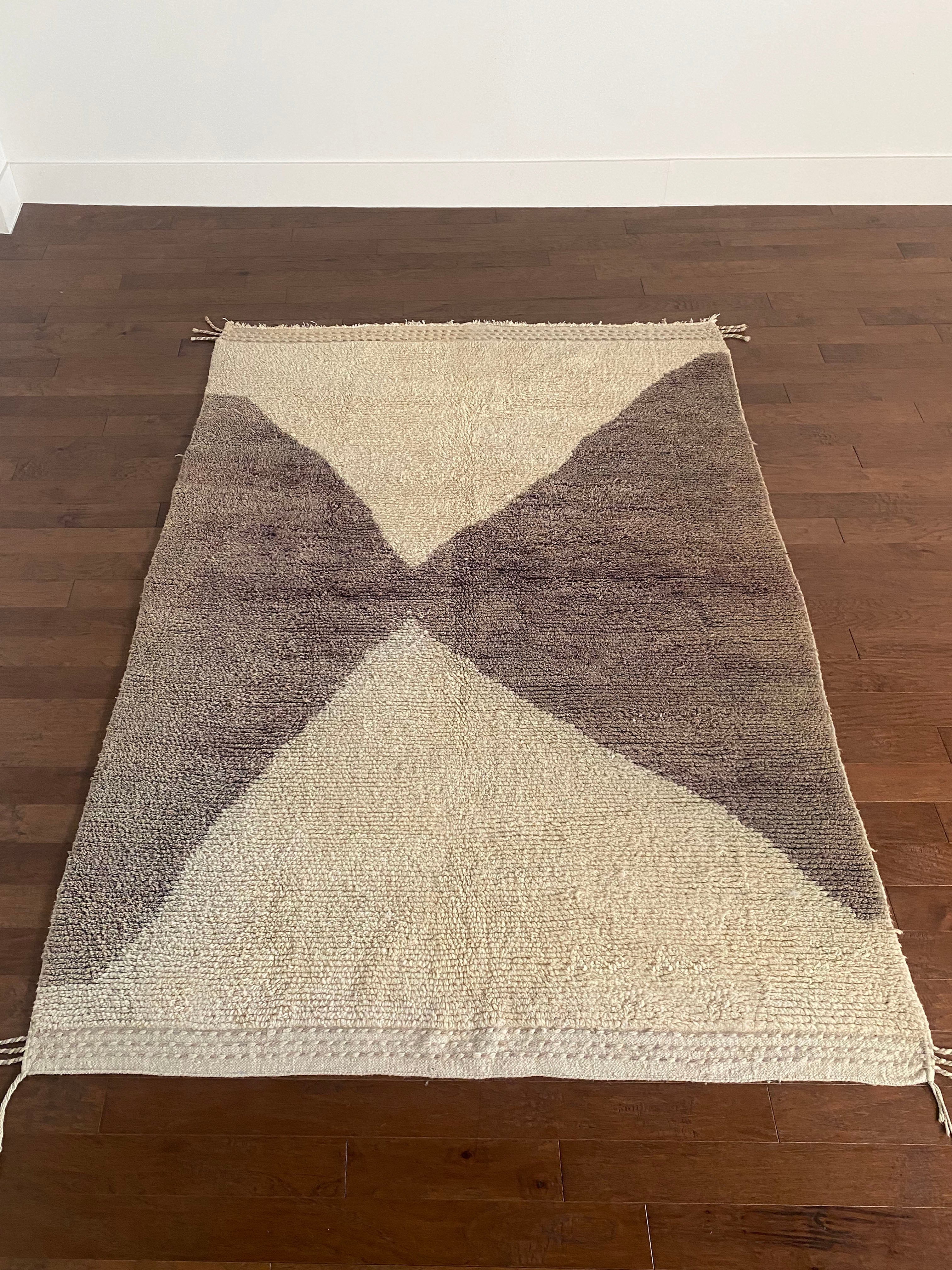 a vintage berber rug with two large taupe diamonds on a cream wool field