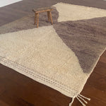a vintage berber rug with two large taupe diamonds on a cream wool field