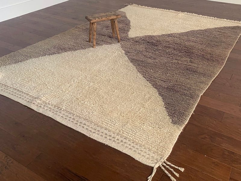 a vintage berber rug with two large taupe diamonds on a cream wool field