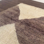 a vintage berber rug with two large taupe diamonds on a cream wool field