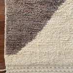 a vintage berber rug with two large taupe diamonds on a cream wool field