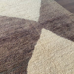 a vintage berber rug with two large taupe diamonds on a cream wool field