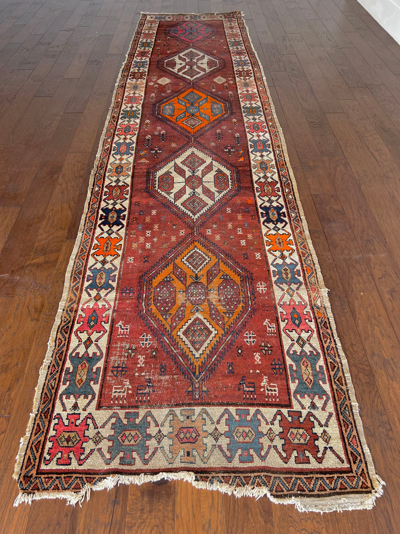 Nora: an antique Heriz runner circa 1920, with a terracotta field and bright neon medallions