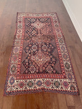 an antique shiraz qashqai rug with a dark blue field and red accents