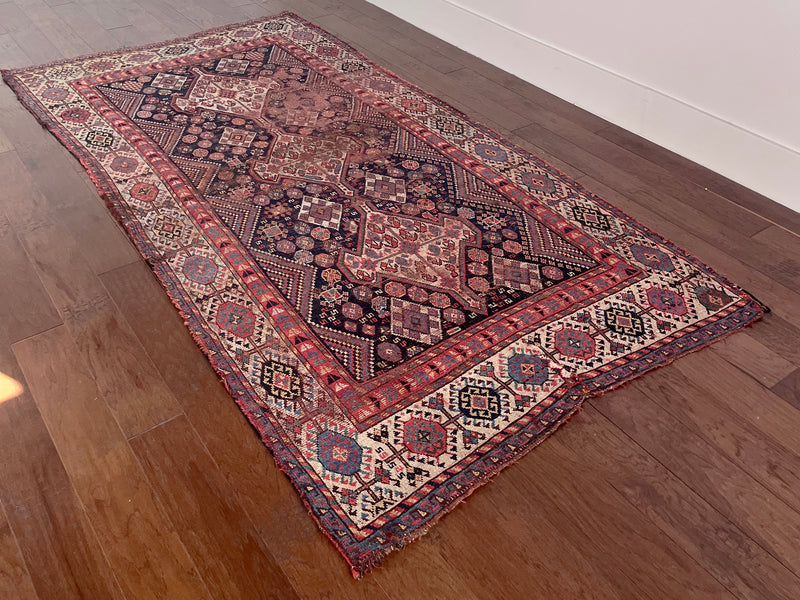 an antique shiraz qashqai rug with a dark blue field and red accents