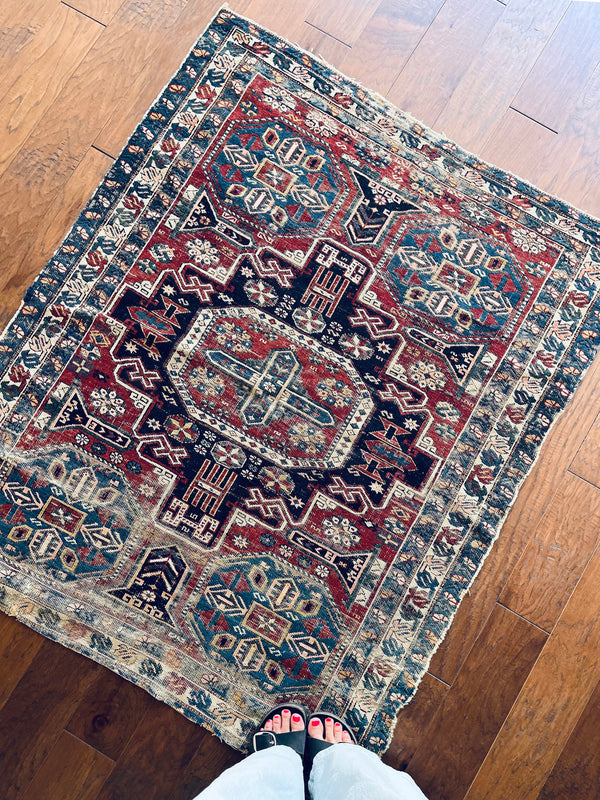 an antique caucasian shirwan rug with teal border, 4 blue corner medallions and a red field