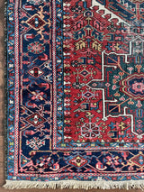 an antique heriz karajah rug with a red field and forest green and navy accents