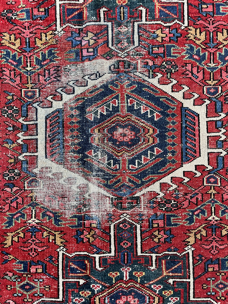 an antique heriz karajah rug with a red field and forest green and navy accents