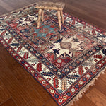 an antique caucasian rug with red and blue accents and a large geometric pattern
