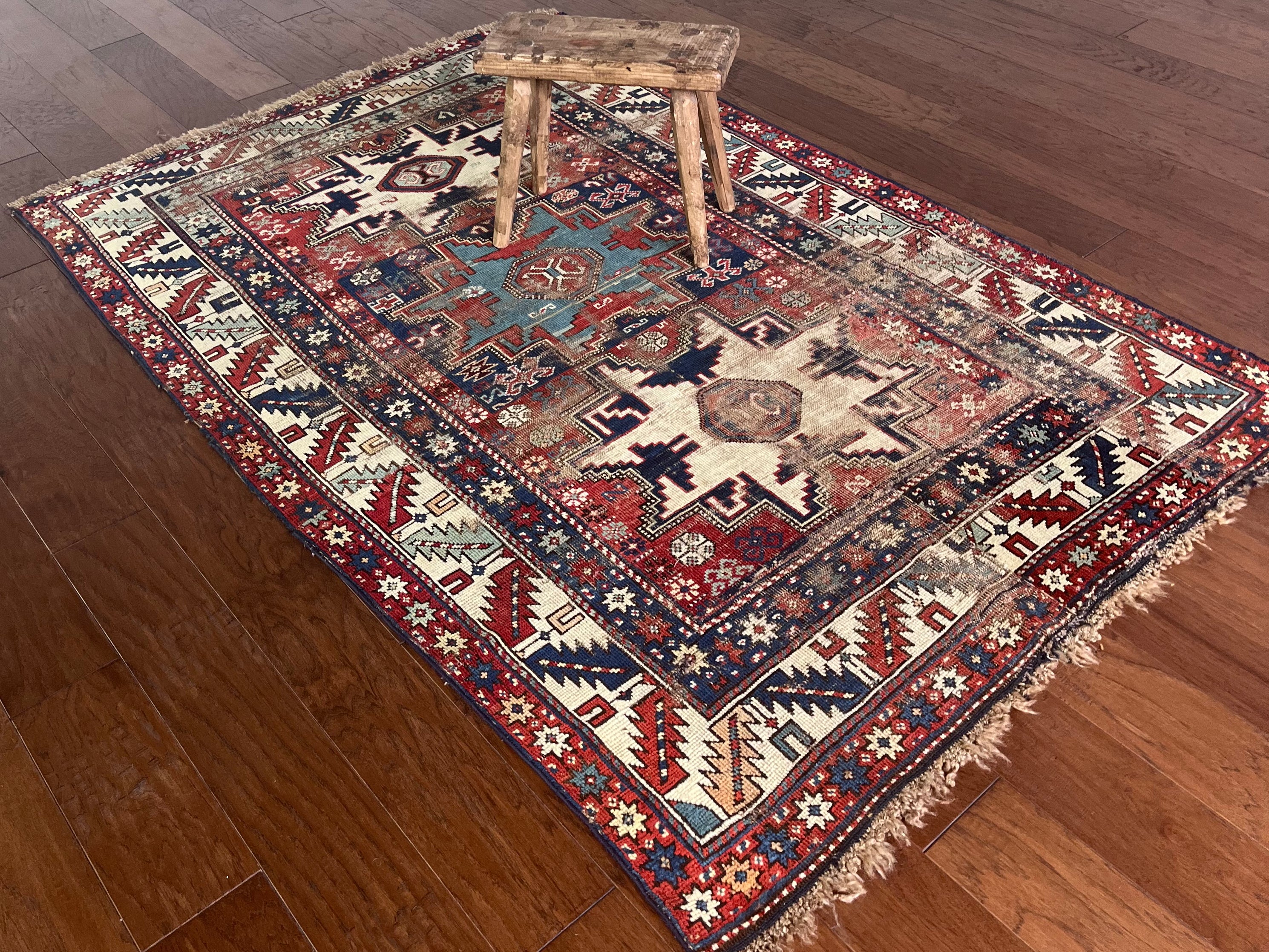 an antique caucasian rug with red and blue accents and a large geometric pattern